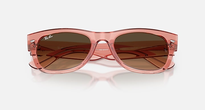 Pink sunglasses with brown lenses on a white background