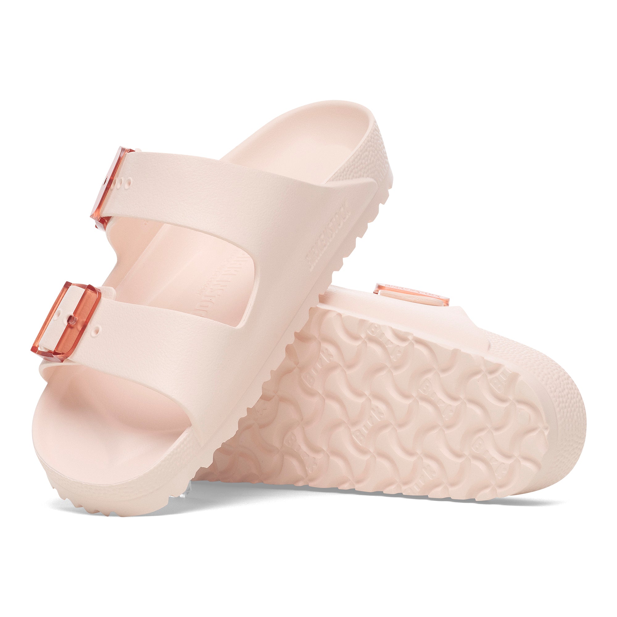 Pair of beige sandals with brown buckles on a white background