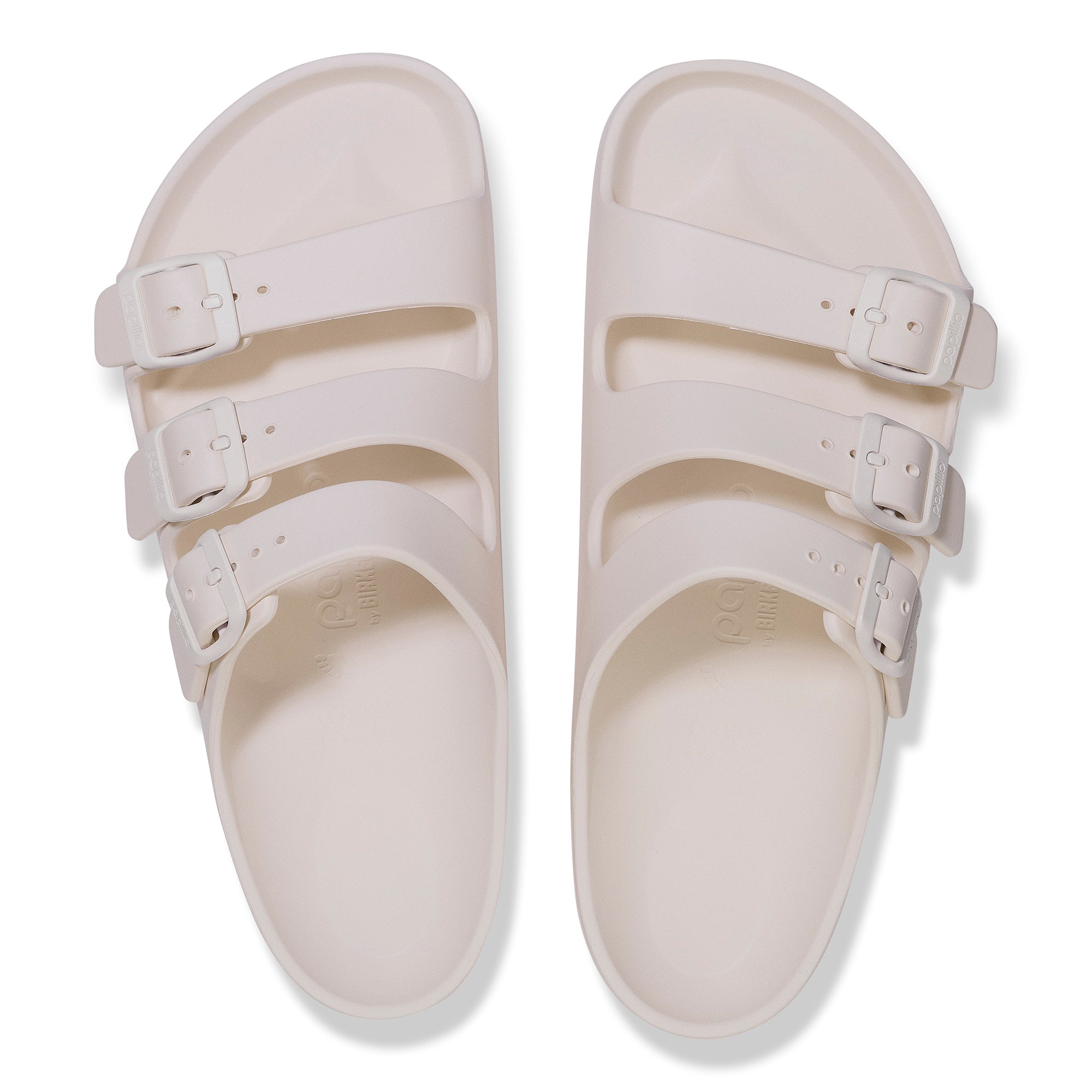 Pair of white sandals with multiple straps on a white background