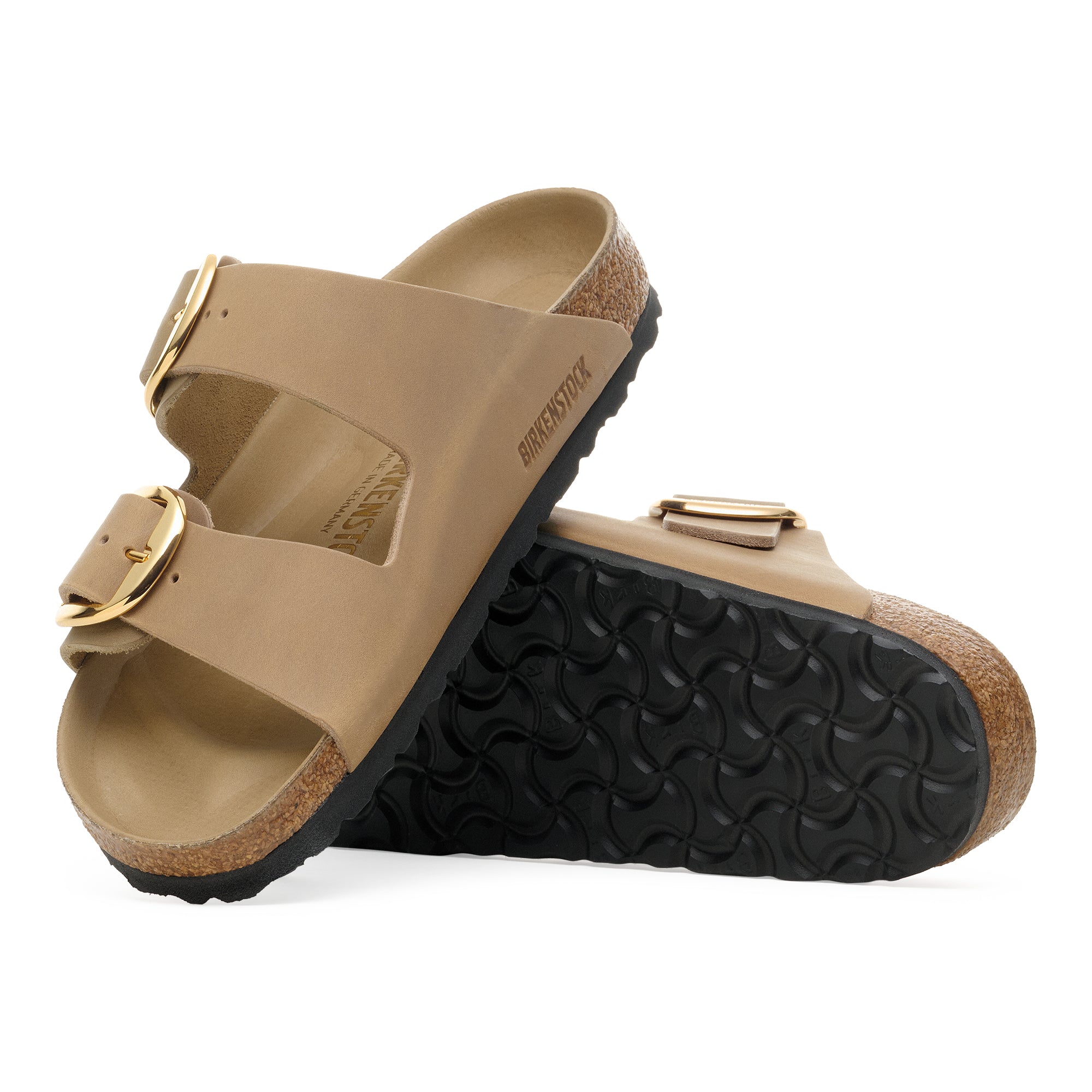 Pair of tan sandals with gold buckles on a white background