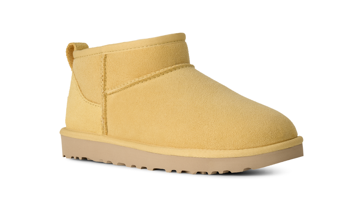 A single ankle-height suede bootie in a soft mustard yellow color, shown from a three-quarters angle against a plain white background.