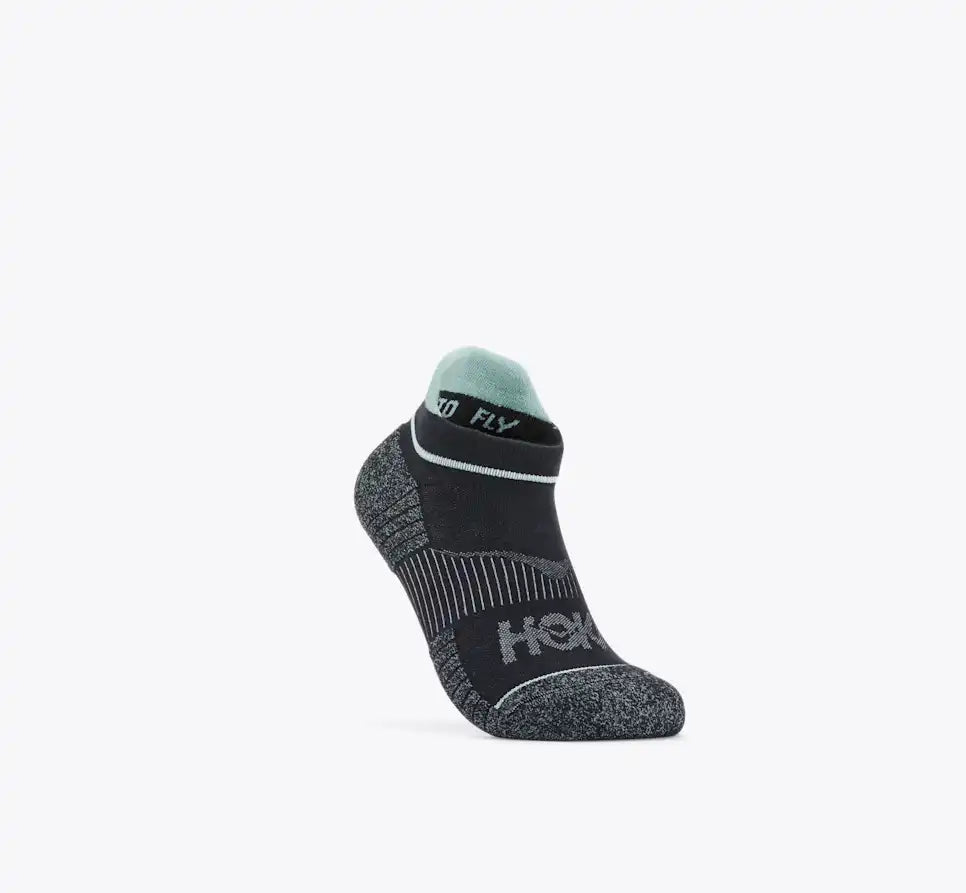 A single low-cut athletic sock in black and dark gray with a mint green cuff, featuring the HOKA logo on the side and '360 FLY' on the band, shown against a plain white background.
