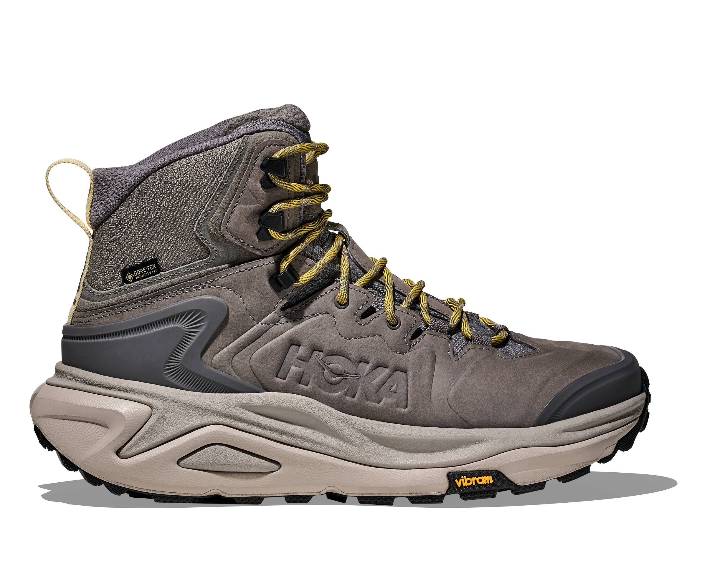 A Hoka mid-top hiking boot in gray suede and synthetic materials, featuring yellow laces, a beige midsole, and a black Vibram outsole, shown against a plain white background.