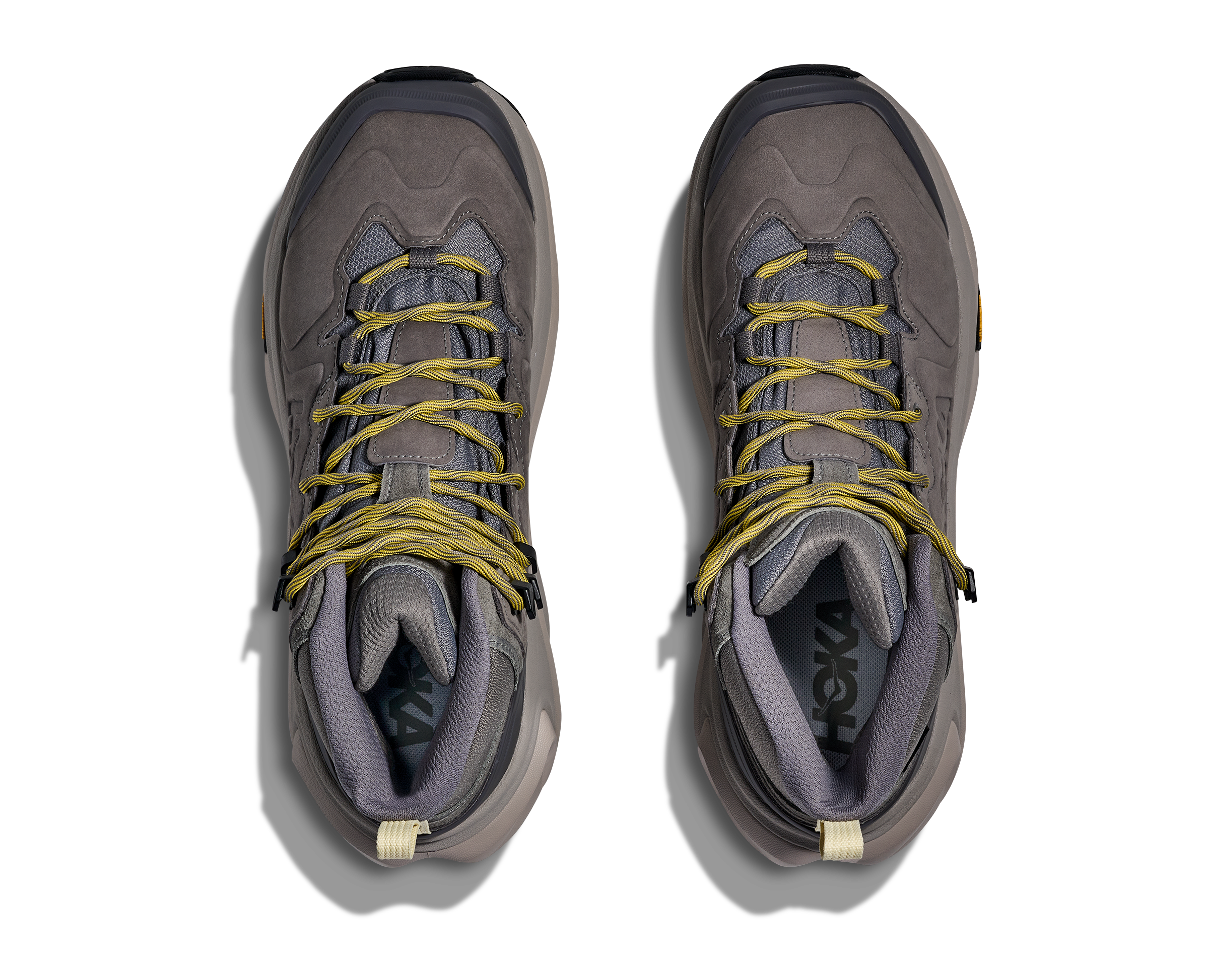 A pair of Hoka hiking boots in gray suede and mesh with yellow laces, shown from a top-down view on a white background.