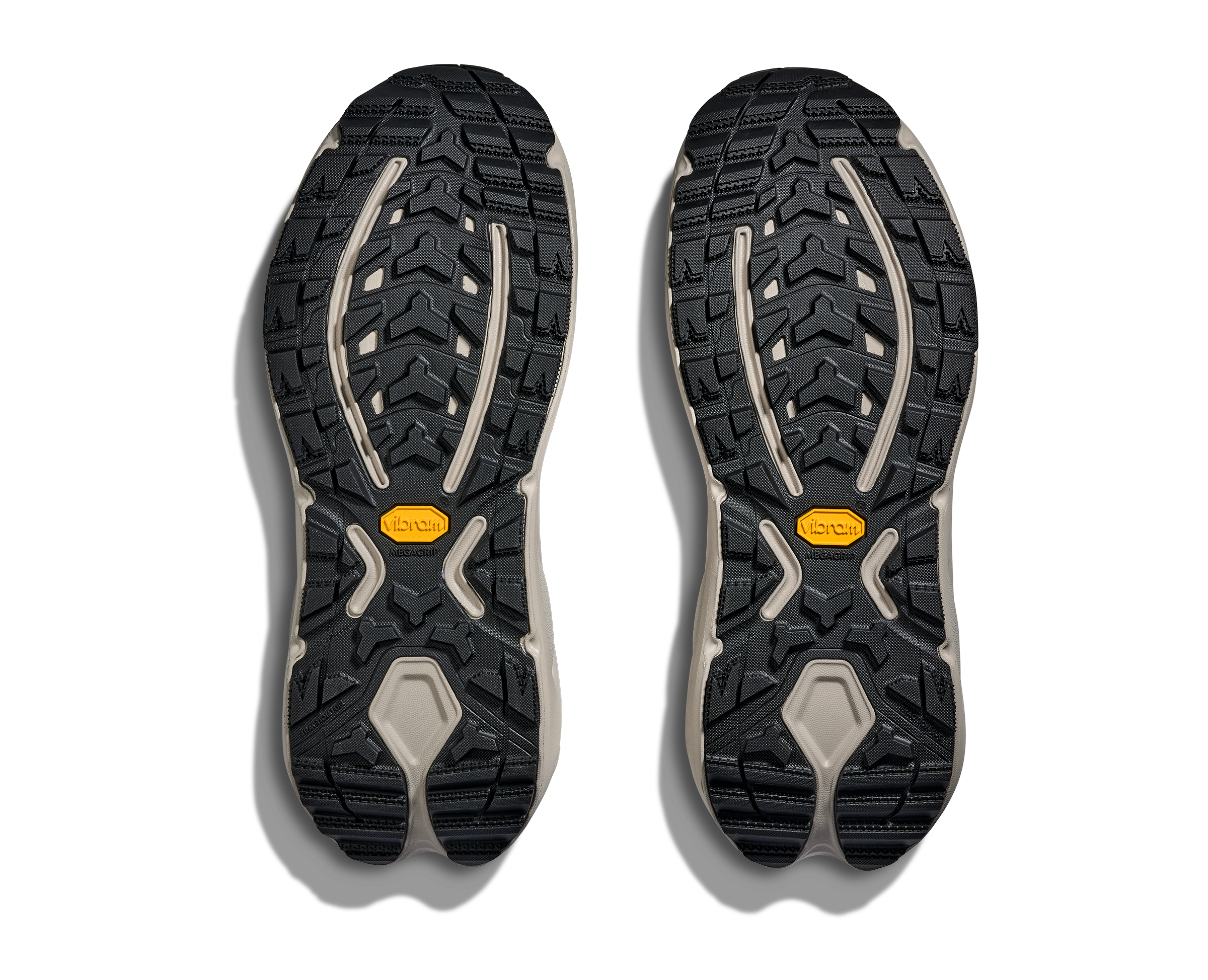 Top-down view of a pair of hiking shoe soles showing the tread pattern, Vibram branding, and beige midsoles against a white background.