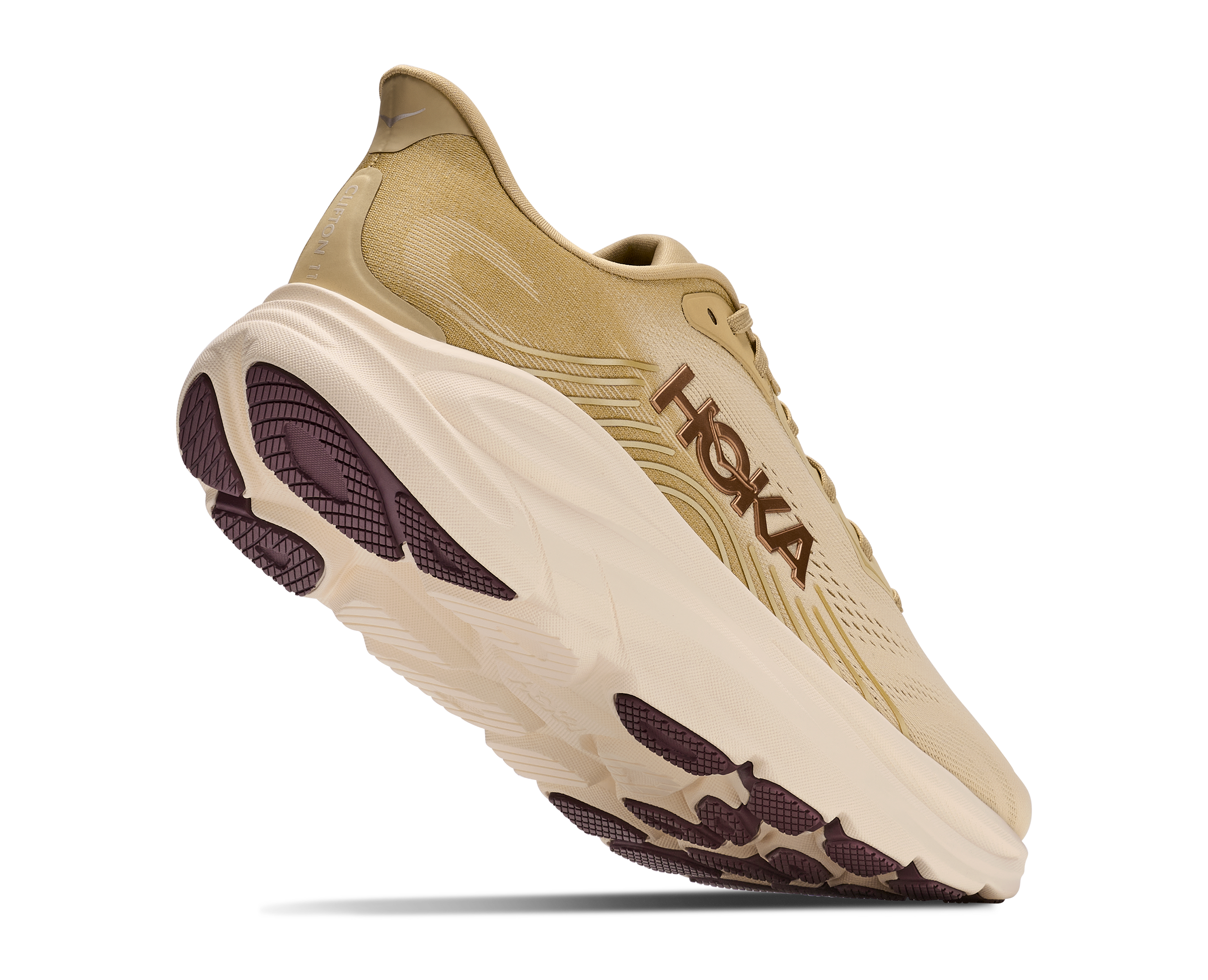 A Hoka running shoe in beige and cream with dark brown accents, shown from a three-quarters angle against a white background.