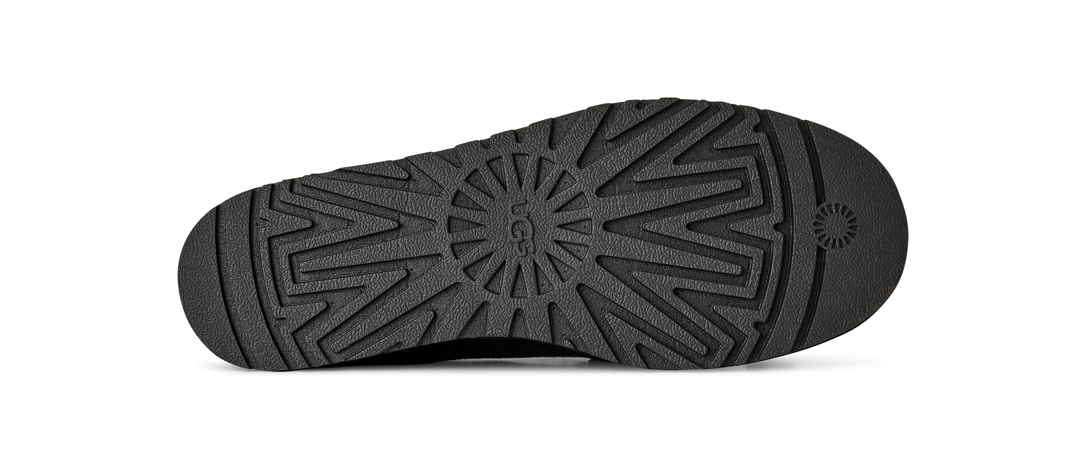The black rubber outsole of a shoe, showing a detailed tread pattern and a small circular logo on the heel, isolated on a white background.
