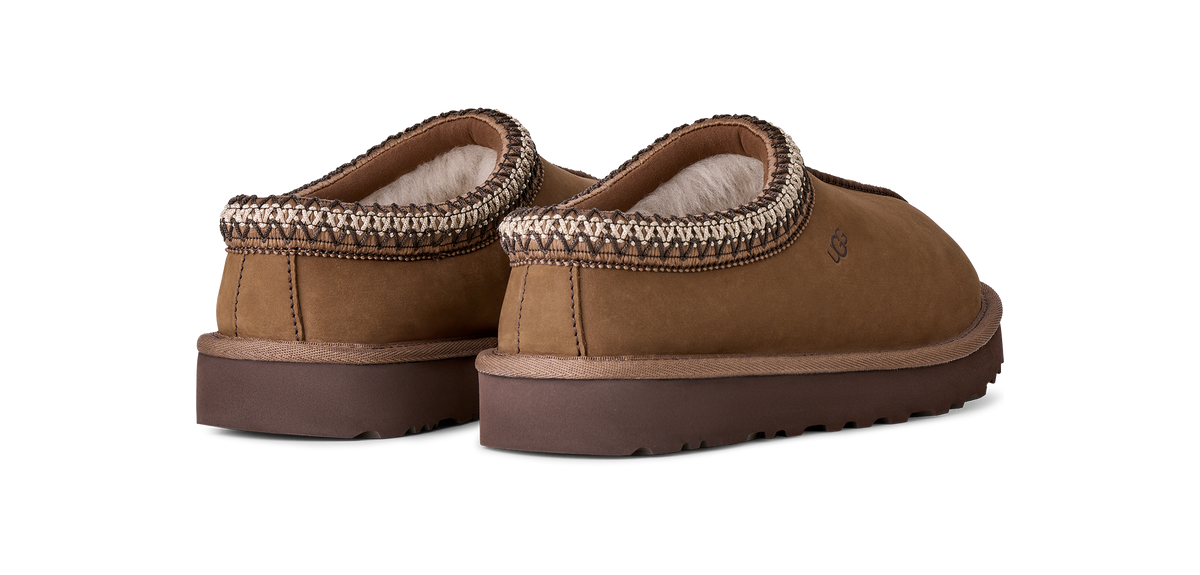 A pair of brown suede slip-on slippers with a textured knit trim and a soft cream lining, shown from a three-quarters angle on a white background.