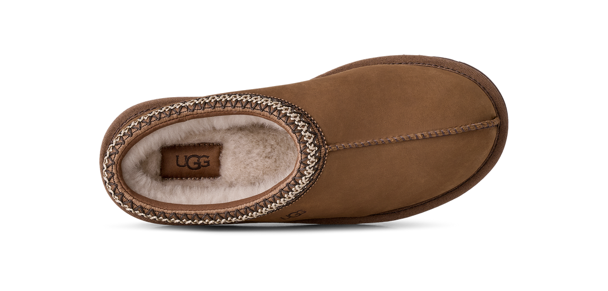 A single UGG slip-on slipper in brown suede with a braided trim and light beige shearling lining, shown from a top-down view on a white background.