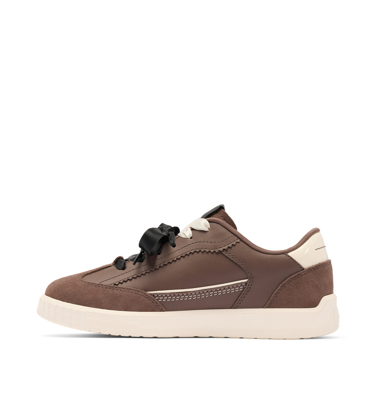 A brown low-top sneaker with a thick cream-colored sole, cream heel tab, and black ribbon laces, shown from a side profile on a white background.