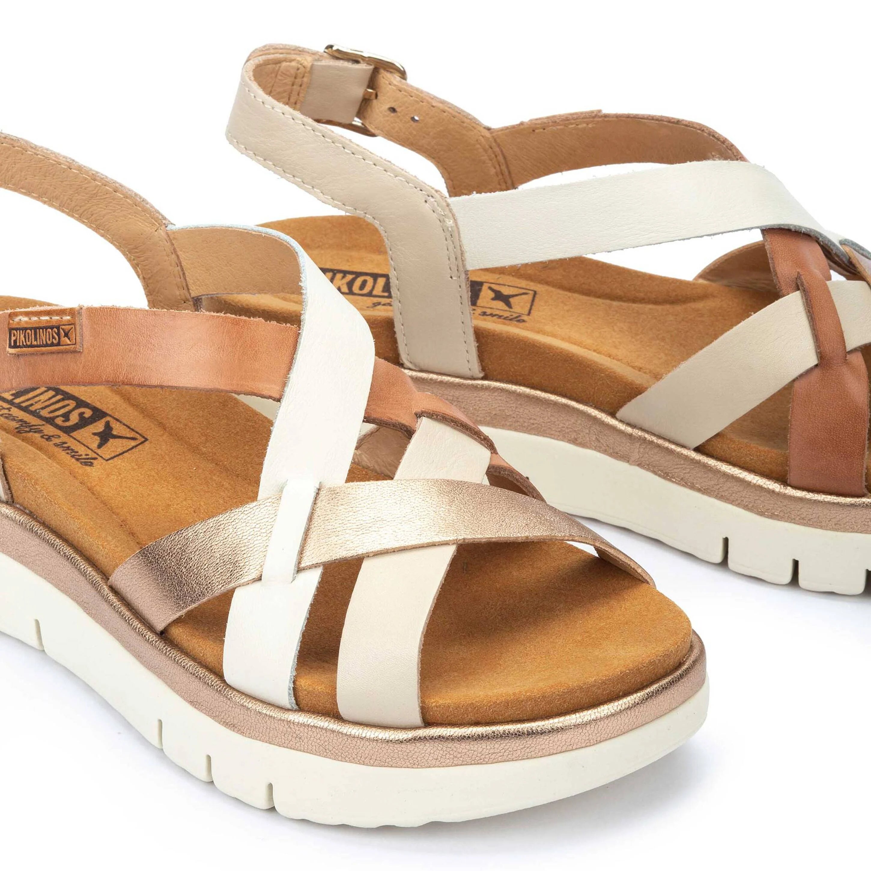 Pair of sandals with brown and white straps on a white background