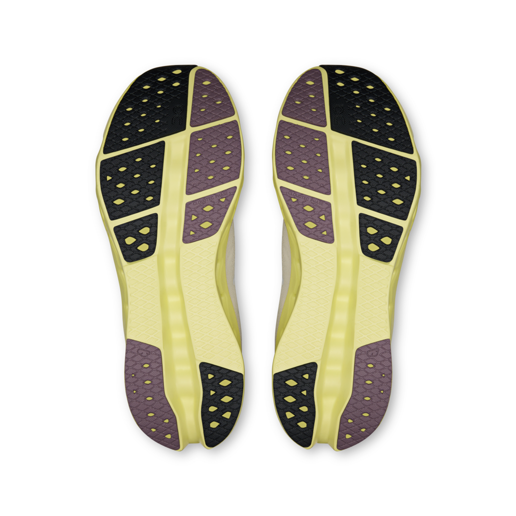 Pair of yellow athletic shoes with black and purple sole pattern on a white background