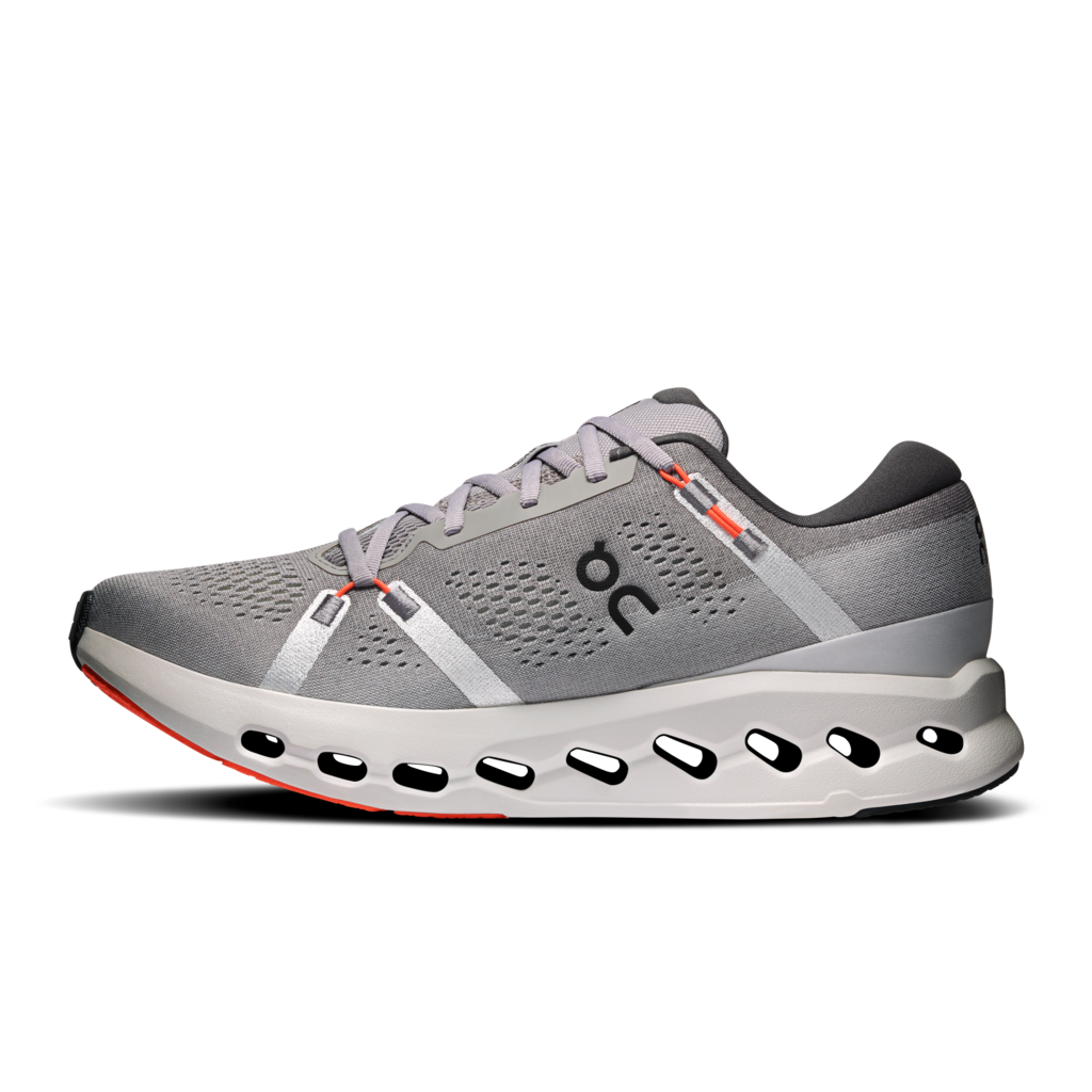 A gray On running shoe with a chunky white and gray sole featuring circular cutouts, gray laces, and small orange accents, shown against a plain white background.