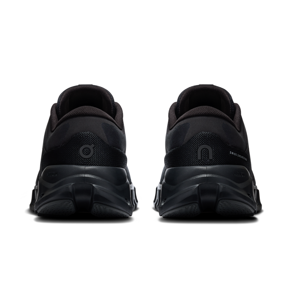 Black athletic sneakers shown from the rear, featuring chunky black soles and subtle logo details on a plain white background.