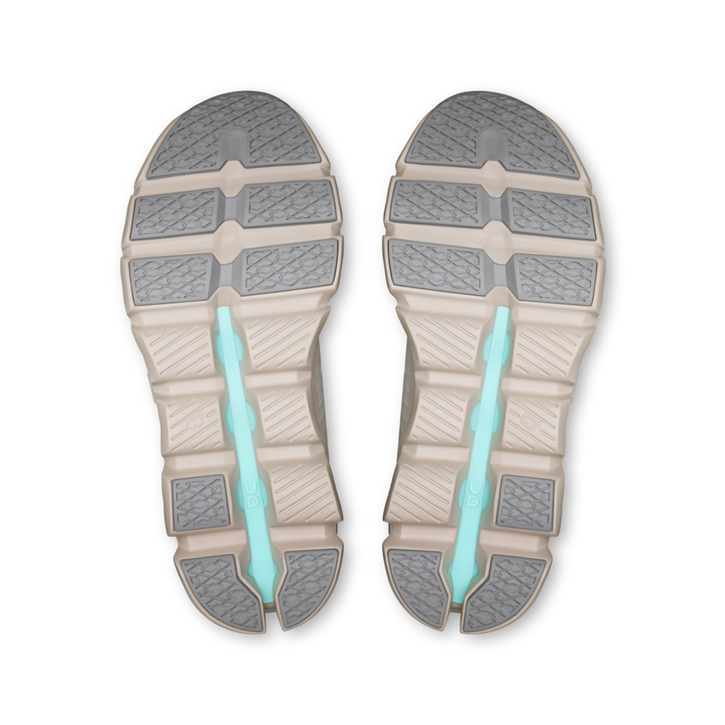 Top-down view of a pair of athletic shoe soles, showing a beige and gray segmented tread pattern with a glowing light blue-green central channel.