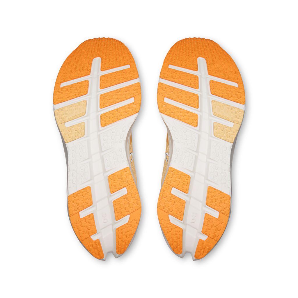 Top-down view of a pair of athletic shoes showing the orange and white outsoles against a plain white background.