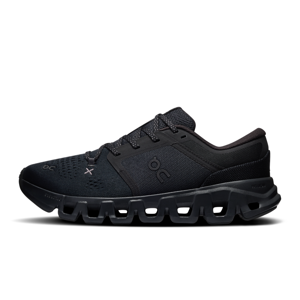 A black athletic sneaker shown from the side profile against a solid white background. The shoe features a breathable mesh upper, matching black laces, and a distinctive chunky, cushioned sole with cutout details.