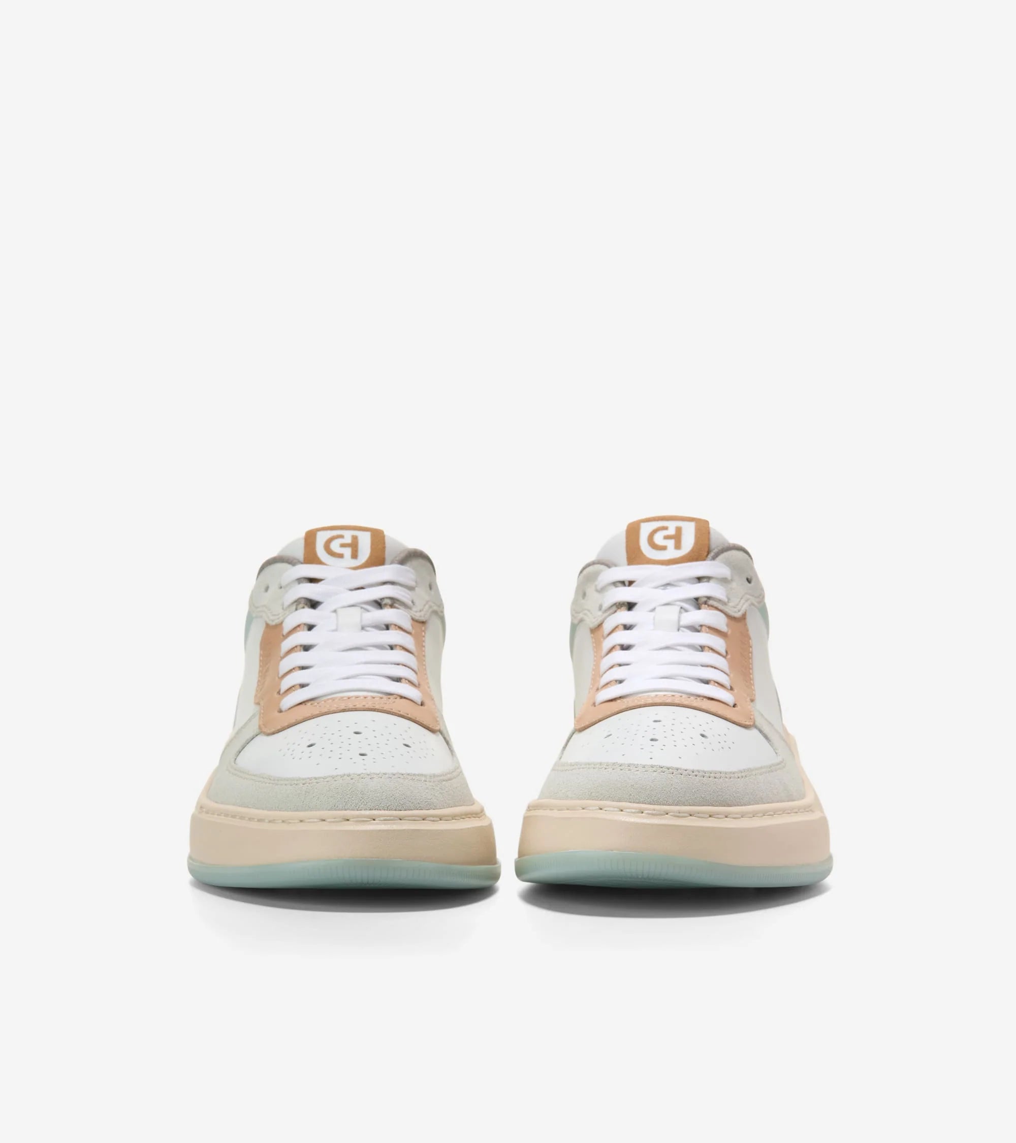 Pair of white sneakers with tan accents on a white background