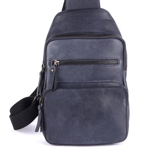 A dark navy blue faux leather sling bag with a front zippered pocket and a black adjustable shoulder strap, shown against a plain white background.