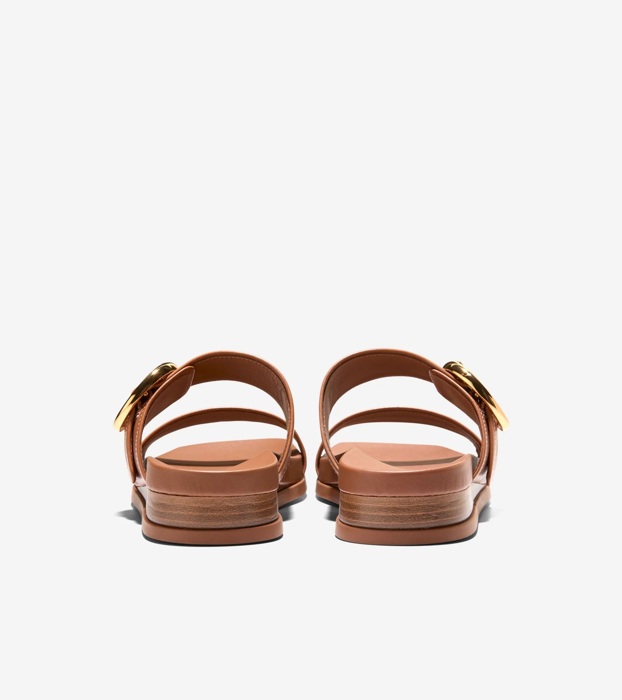 Pair of brown sandals with gold straps on a light gray background