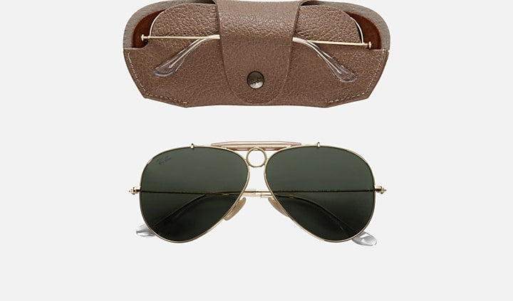 Aviator sunglasses with gold frame and dark lenses, displayed with a brown leather case on a white background.