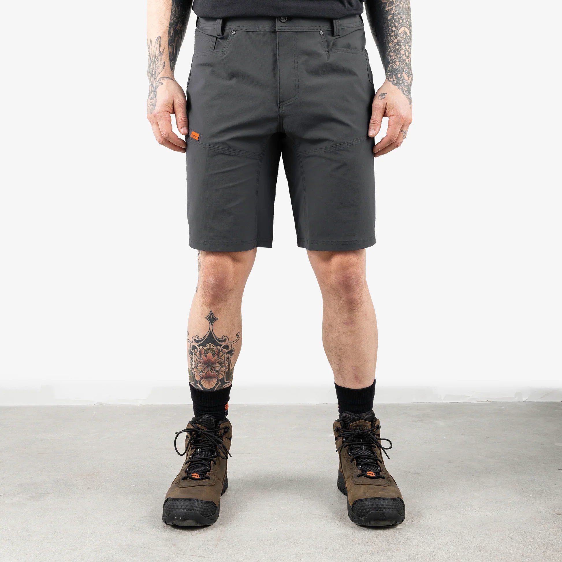 Person wearing gray shorts and hiking boots on a plain background