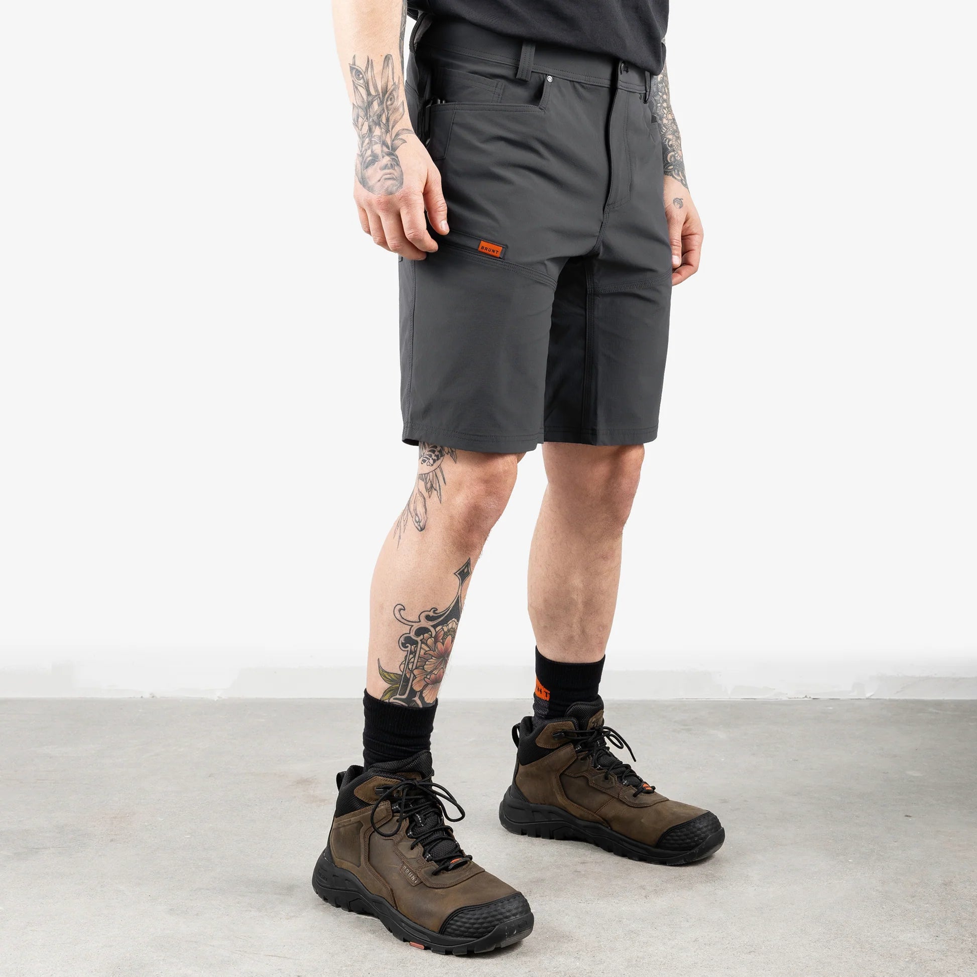 Person wearing gray shorts and brown hiking boots on a light background