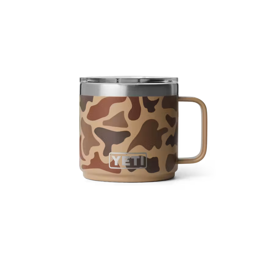 A YETI insulated mug with a brown and tan camouflage pattern, a stainless steel rim, and a matching handle, shown on a white background.