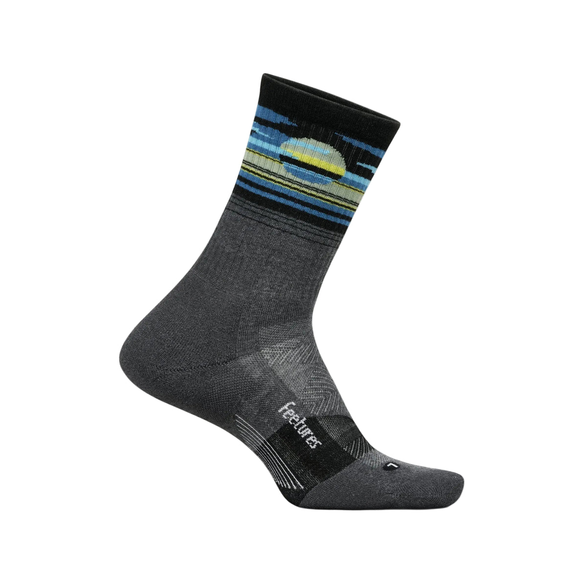 A single crew sock in dark gray with a colorful sunset stripe pattern near the cuff, featuring the 'feeturas' brand name on the heel area, set against a solid off-white background.