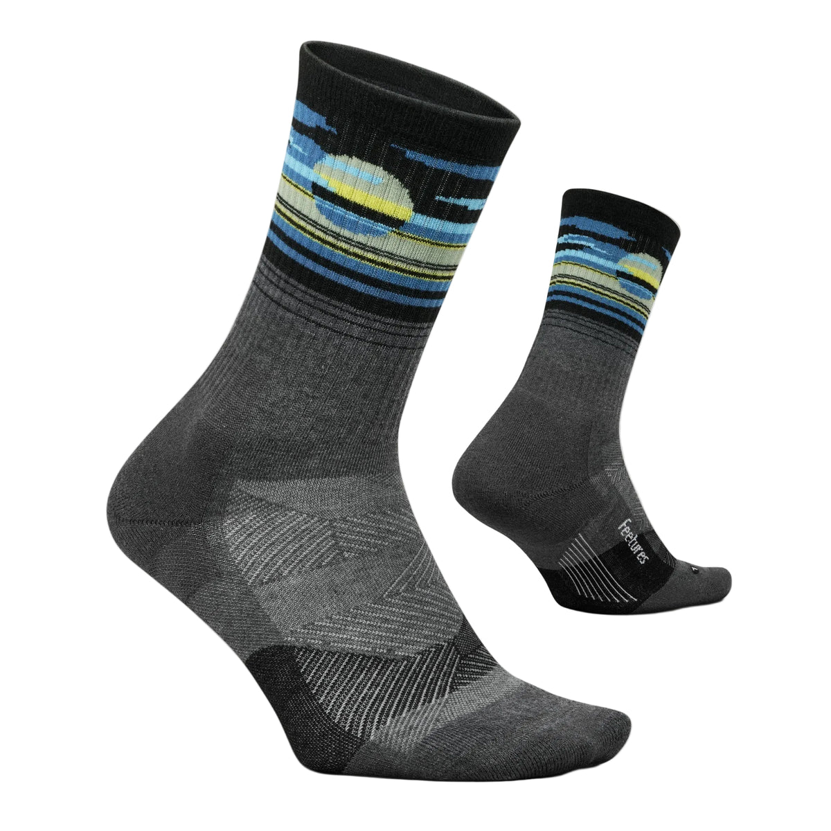 A pair of crew socks shown on invisible forms against a light off-white background. The socks are dark gray with a patterned cuff featuring blue, yellow, and black stripes, and a small white on the heel area of the rear sock.