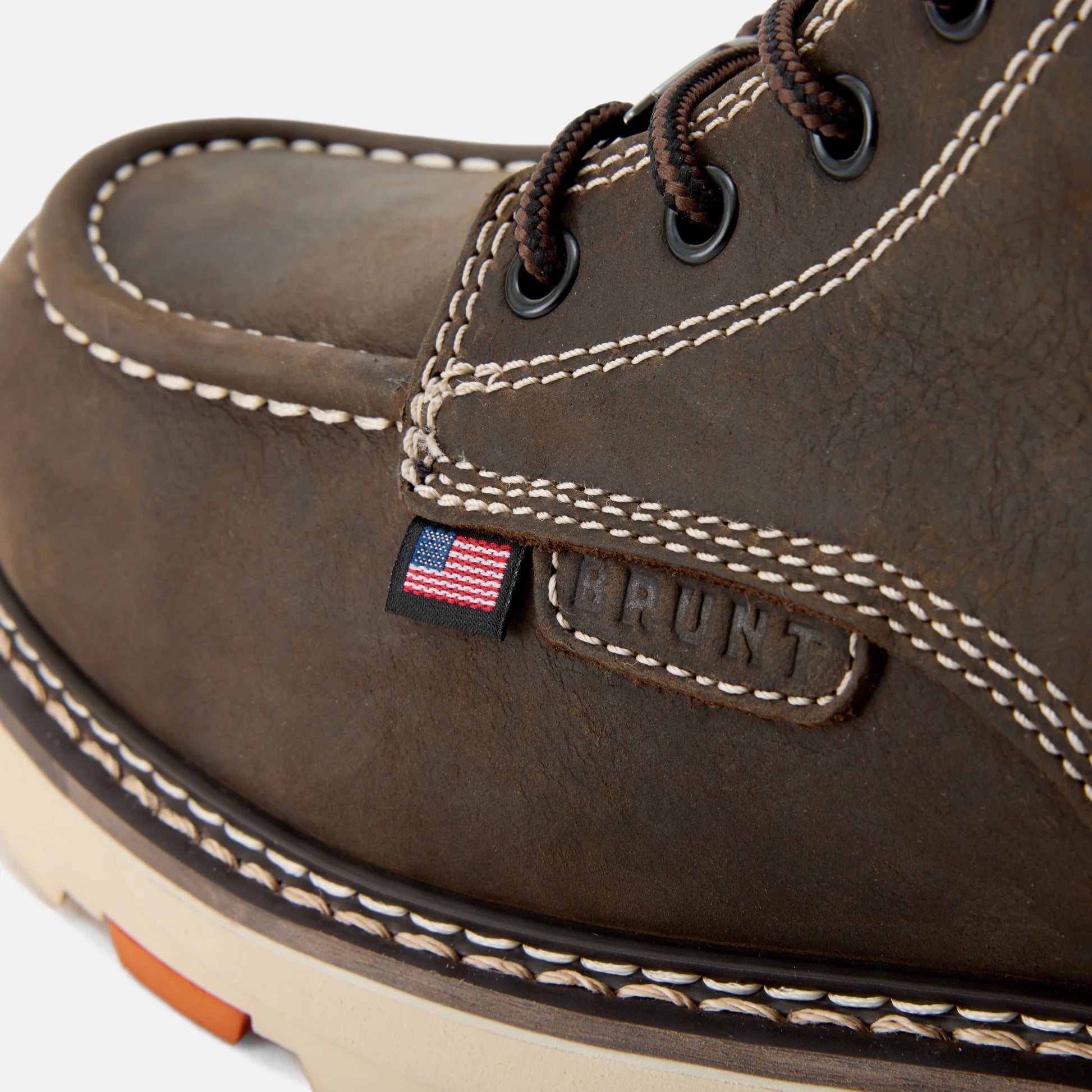 Close-up of a brown leather boot with 'Brunt' branding and American flag detail on a white background.