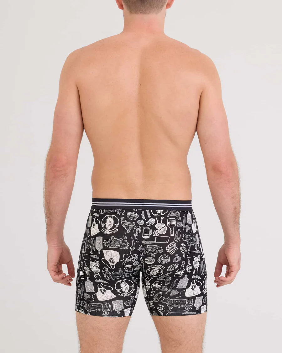 Man wearing black boxer briefs with white graphic design on a plain background