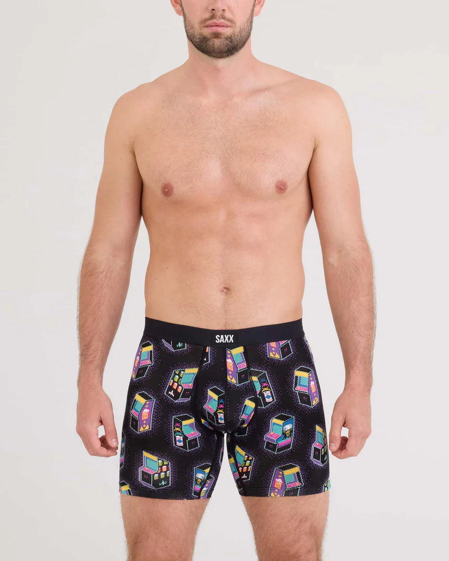 Man wearing black boxer briefs with colorful print on a plain background