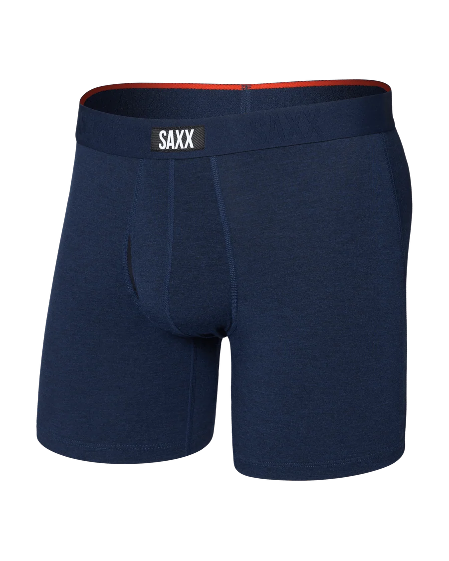 A pair of men's boxer briefs in dark navy blue heather, featuring a contrasting orange-red inner waistband and a white brand label on the front waistband that reads 'SAXX'.