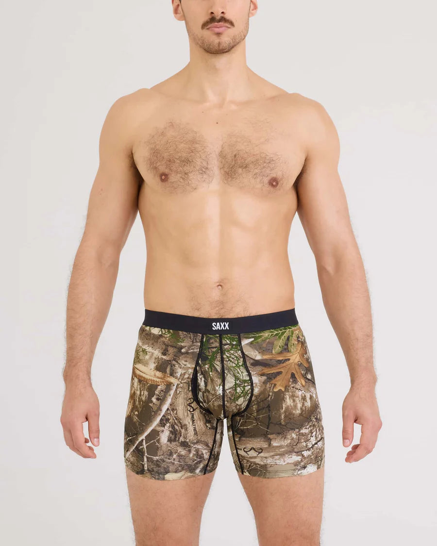 Man wearing camouflage boxer briefs with 'SAXX' branding on a white background