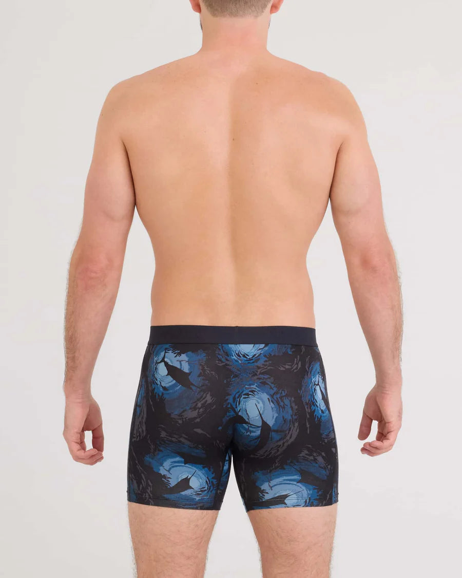 Man wearing black swim trunks with blue shark pattern on a white background