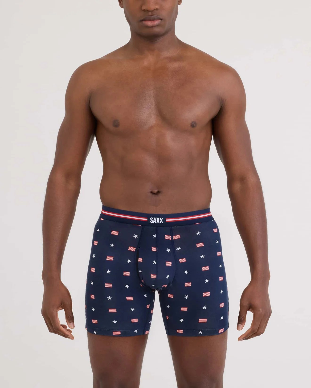 Man wearing navy boxer briefs with red and white pattern on a light gray background
