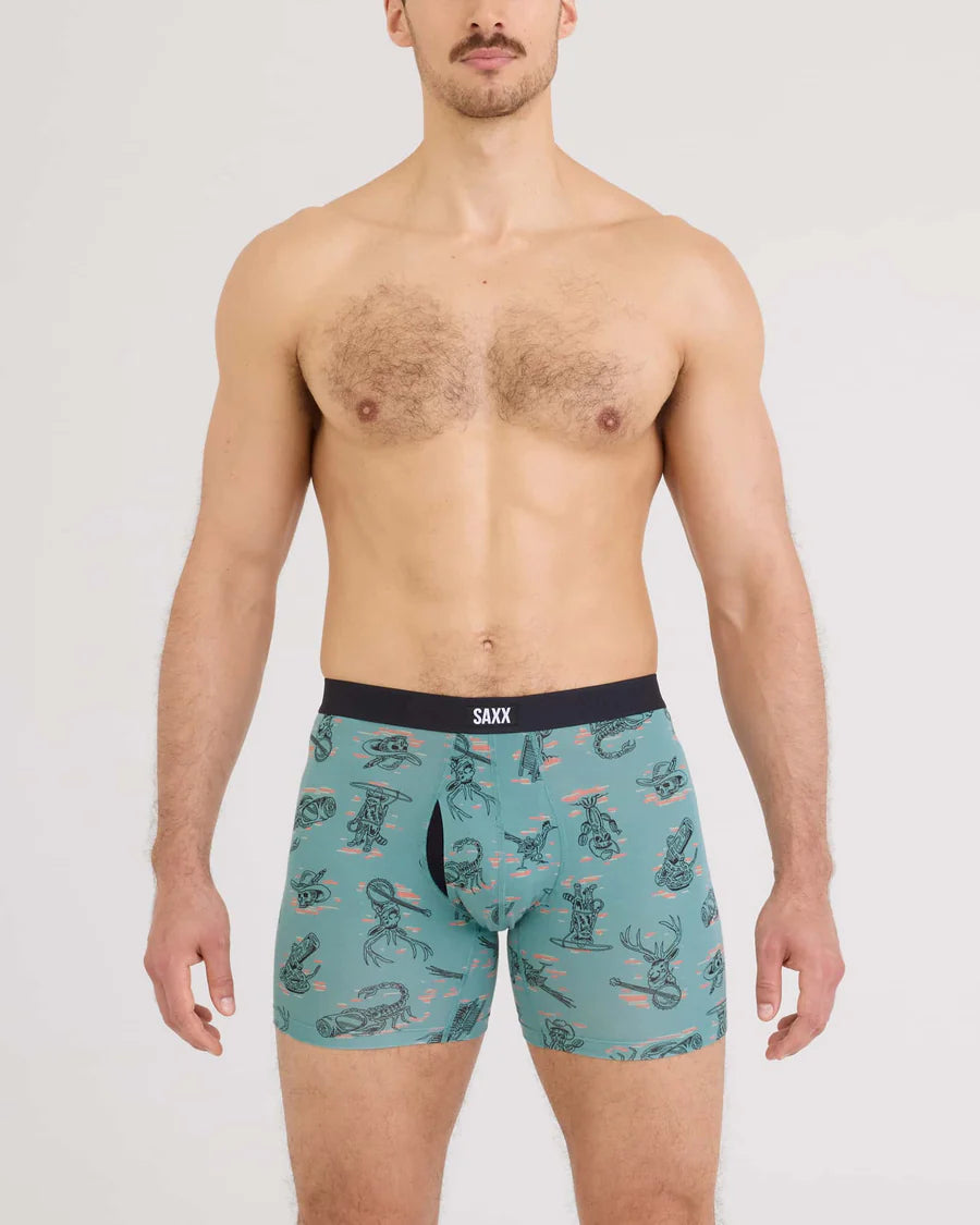 Man wearing teal boxer briefs with a pattern on a white background