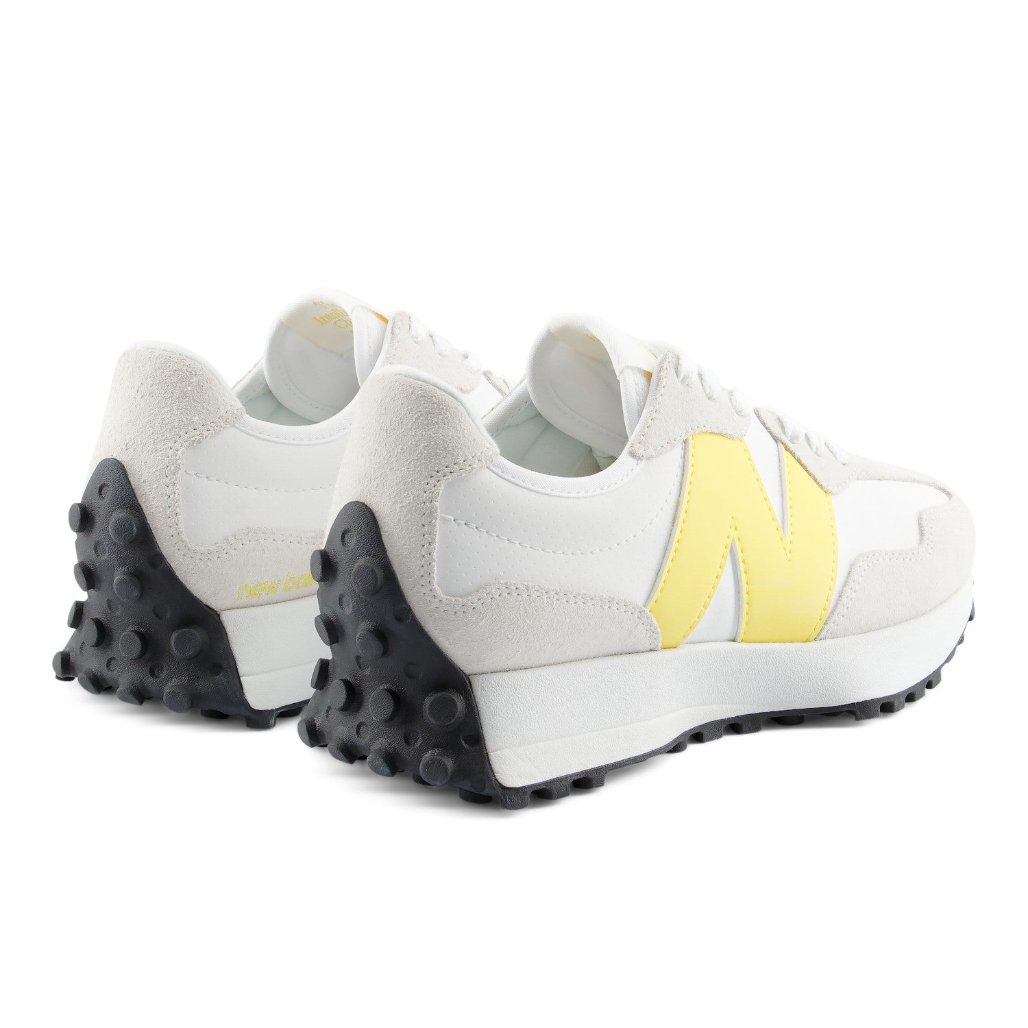 White sneakers with yellow accents and black soles on a white background