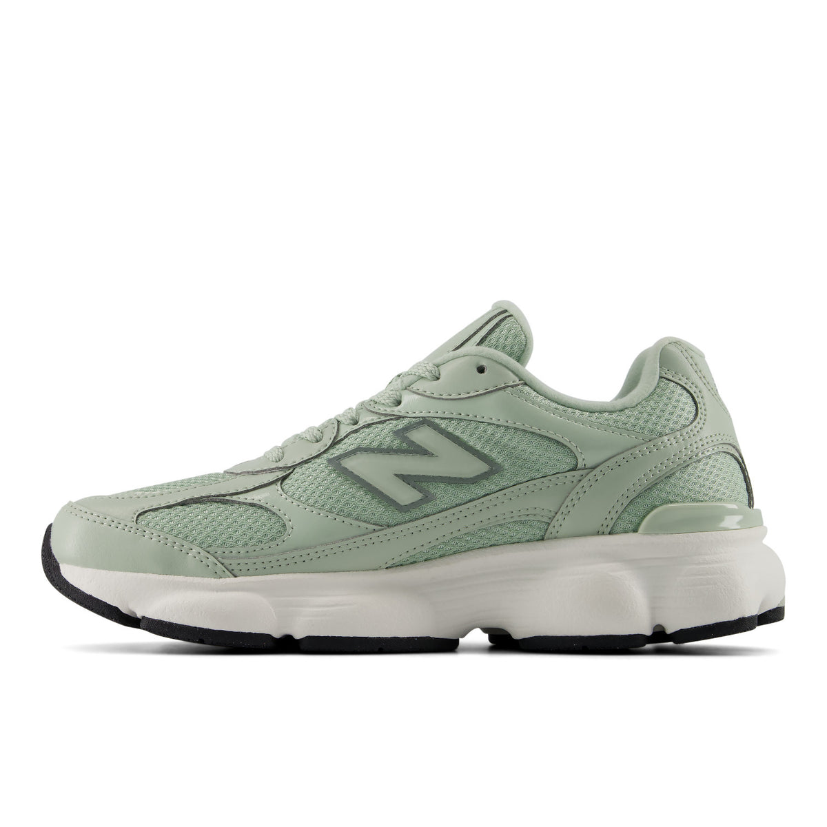 A New Balance sneaker in a light sage green colorway, featuring a mesh and synthetic upper, a matching green 'N' logo, and a chunky white midsole with a black outsole.