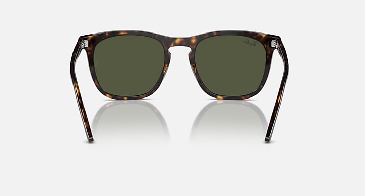 Sunglasses with tortoiseshell frame and green lenses on a white background