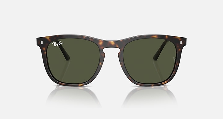 Sunglasses with tortoiseshell frame and green lenses on a white background