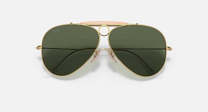 Aviator sunglasses with gold frame and green lenses on a white background