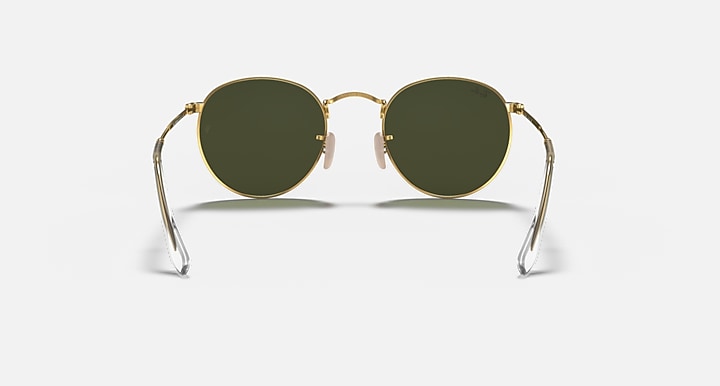 Sunglasses with gold frame and green lenses on a white background