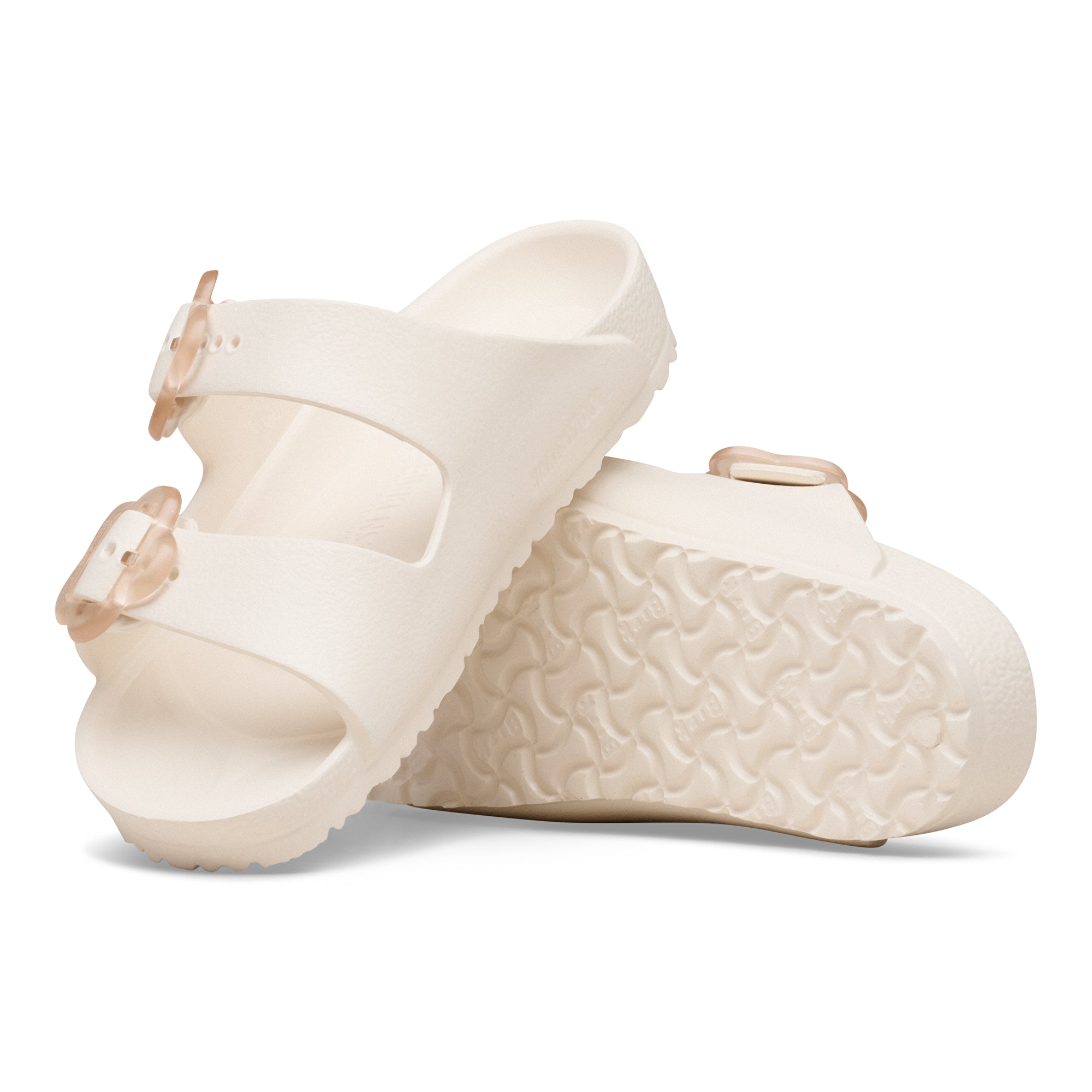 Pair of cream-colored sandals with textured sole on a white background
