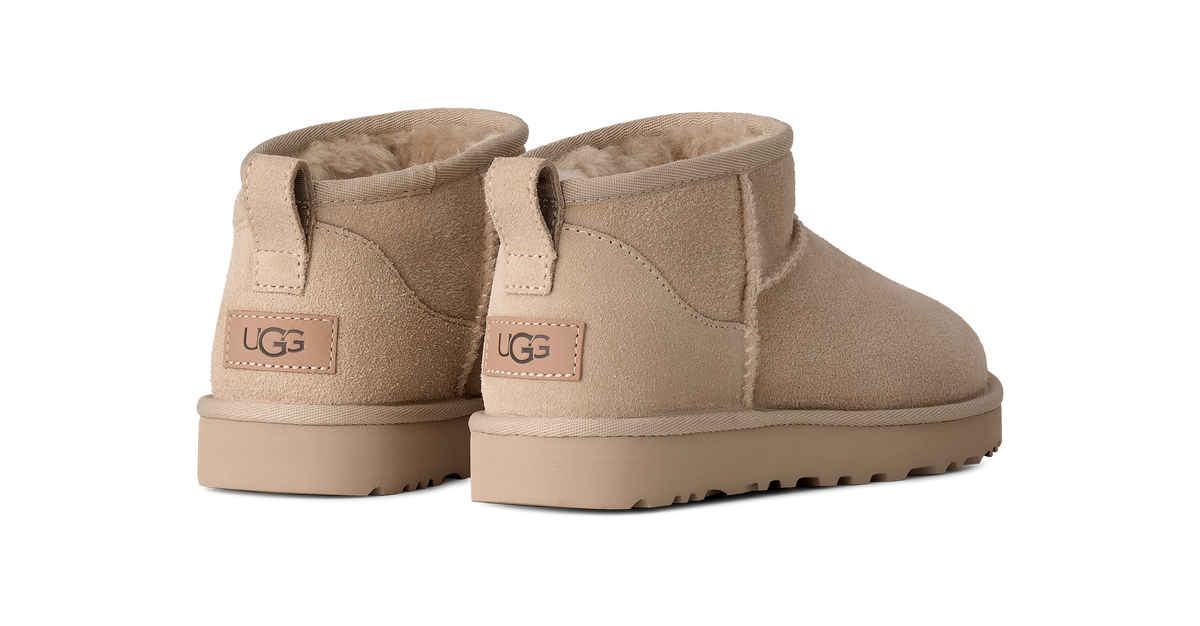 A pair of beige UGG Mini boots with shearling lining, shown from the back on a white background.