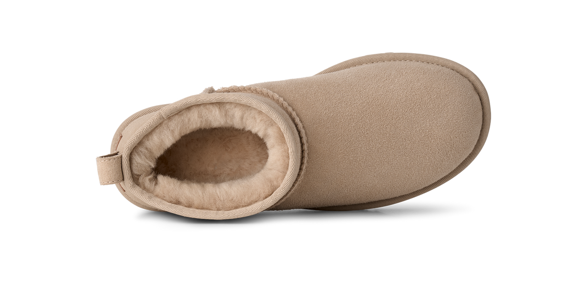 A single beige suede ankle boot with a soft cream shearling lining, shown from a side profile view on a white background.