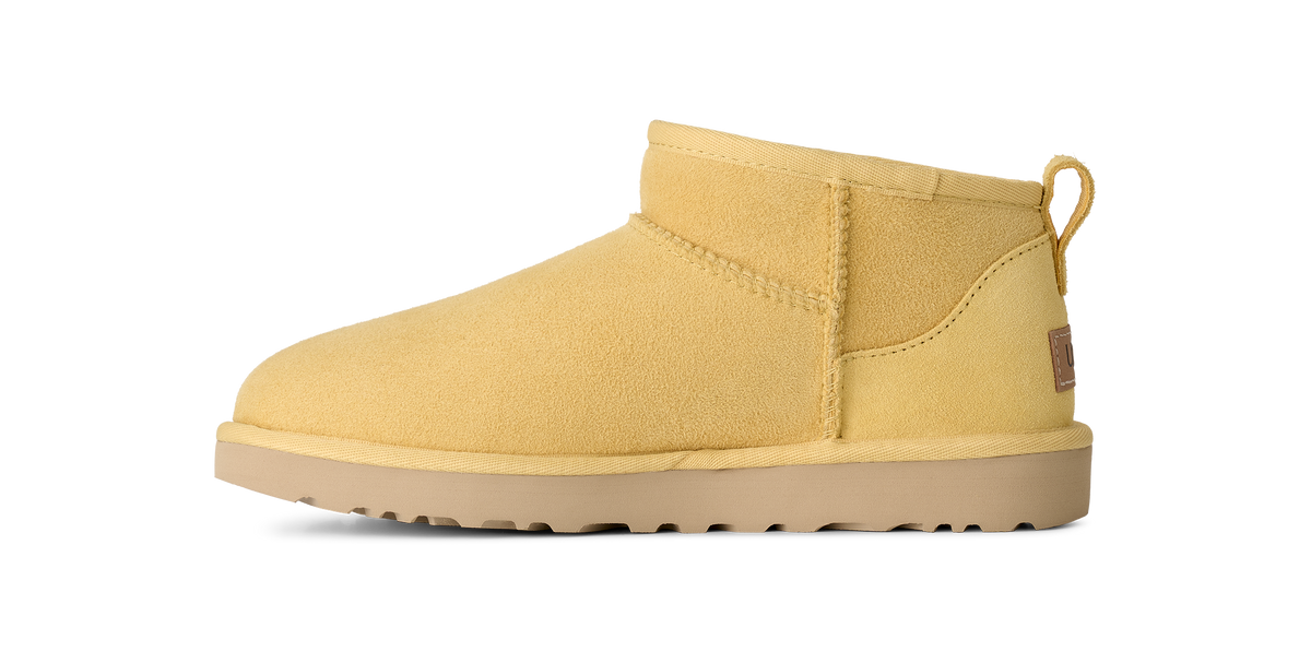 A single yellow suede ankle boot with a tan sole, shown in a side profile on a solid white background.