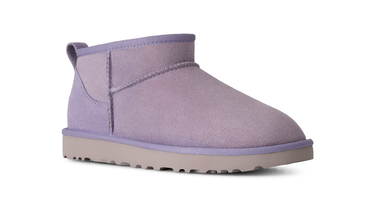 A single mid-calf ankle boot in a dusty lavender purple suede-like material, featuring a thick light gray sole, shown from a side profile on a white background.