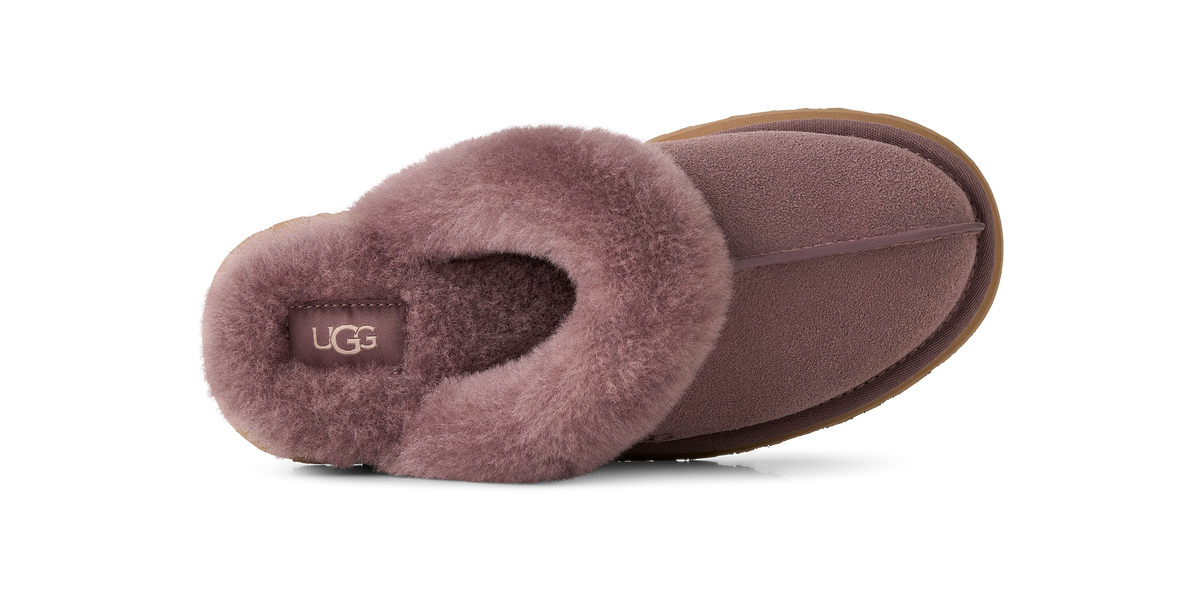 A single UGG slipper in a dusty mauve color, showing the plush faux-fur cuff and the brand name 'UGG' on the insole, set against a plain white background.